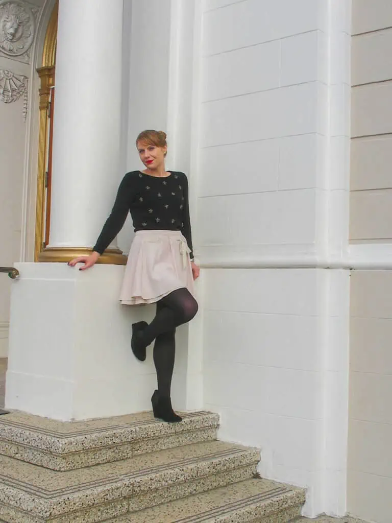 Balletcore styled outfit with pink mini flutter skirt, fitted sweater and black tights.