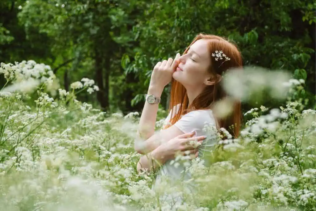 Woman enjoying nature with flowers, embracing self-love and affirmations for beauty
